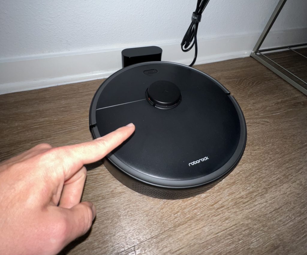 hand pointing to the Roborock Vacuum