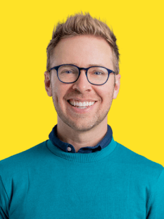 Фотография 2022 года: Ник Грей (выстрел в голову) на желтом фоне, улыбающийся