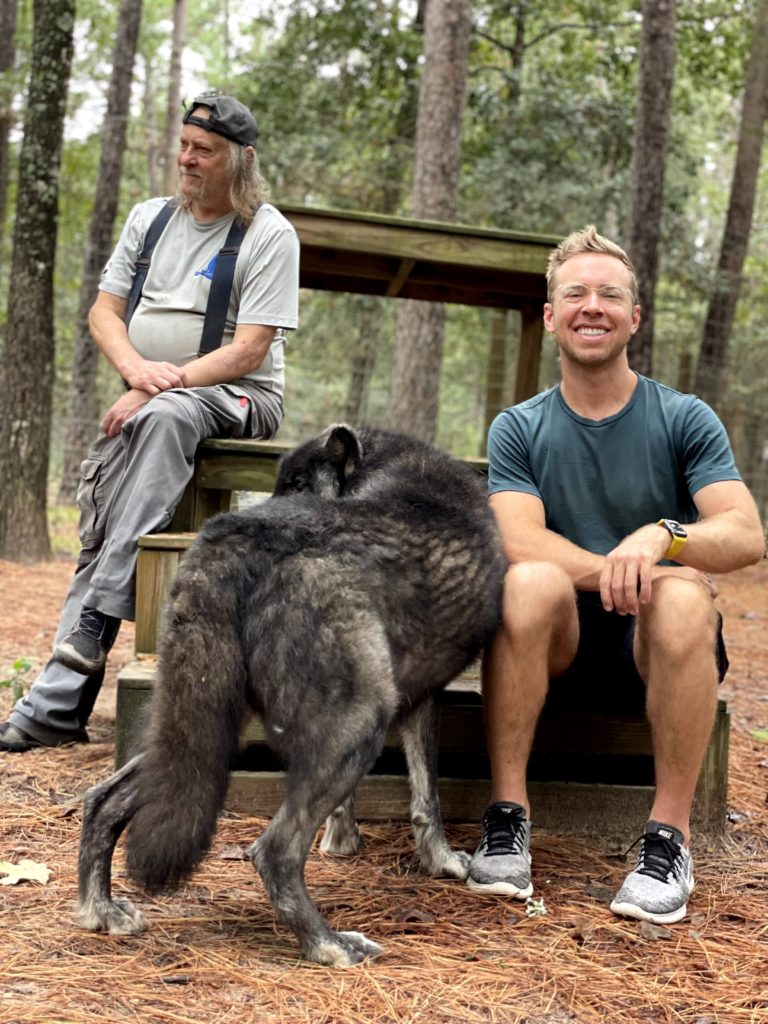 a man sitting in a bench with a wolfdog beside him