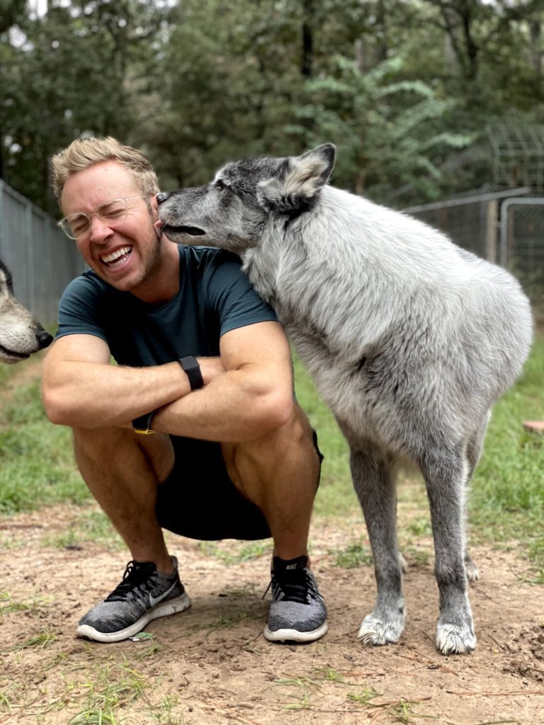 wolfdog licking the face of a man